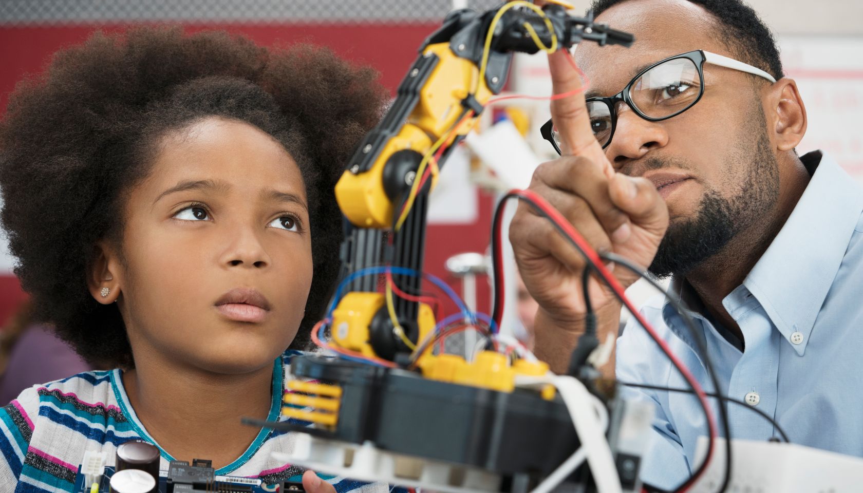 Black teacher helping student with robotics