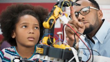 Black teacher helping student with robotics
