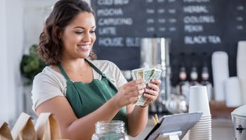 Young female barista counts money from tips jar