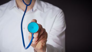 Midsection Of Doctor Holding Stethoscope Against Black Background