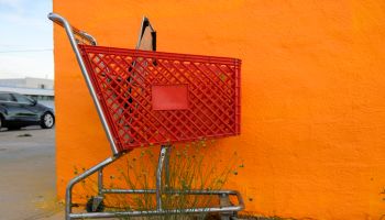 A red shopping cart in front a orang colored wall at Fort Stockton, Texas, USA