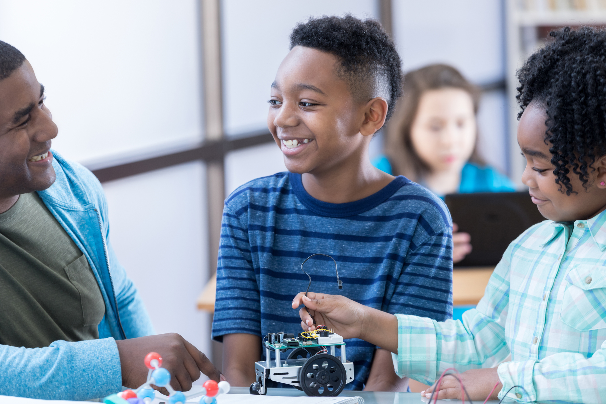 Two students work on robotics project at school with dad