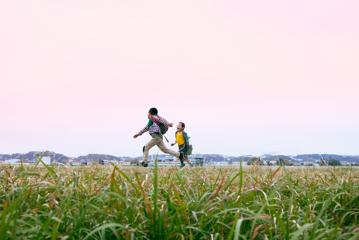 Young boys running at riverbank.