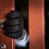 dangerous masked burglar with crowbar breaking into a victim's home door,Home insurance concept