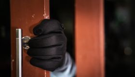 dangerous masked burglar with crowbar breaking into a victim's home door,Home insurance concept