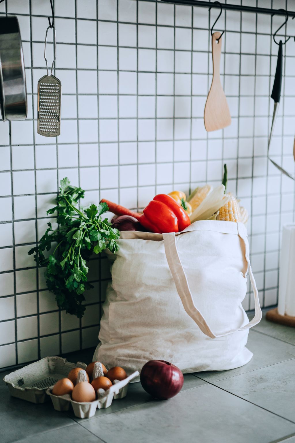 A reusable bag full of colourful and fresh organic vegetables and groceries on the kitchen counter. Zero waste shopping and sustainable lifestyle concept