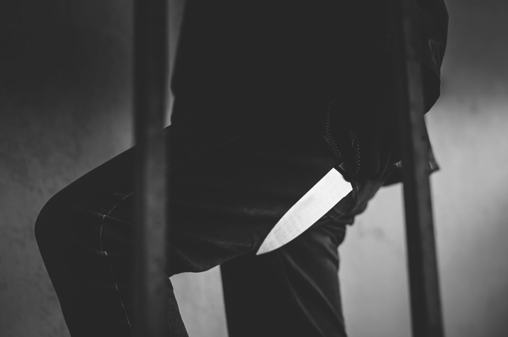 Midsection Of Criminal Holding Knife In Prison