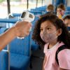 Girl getting her temperature checked on the school bus