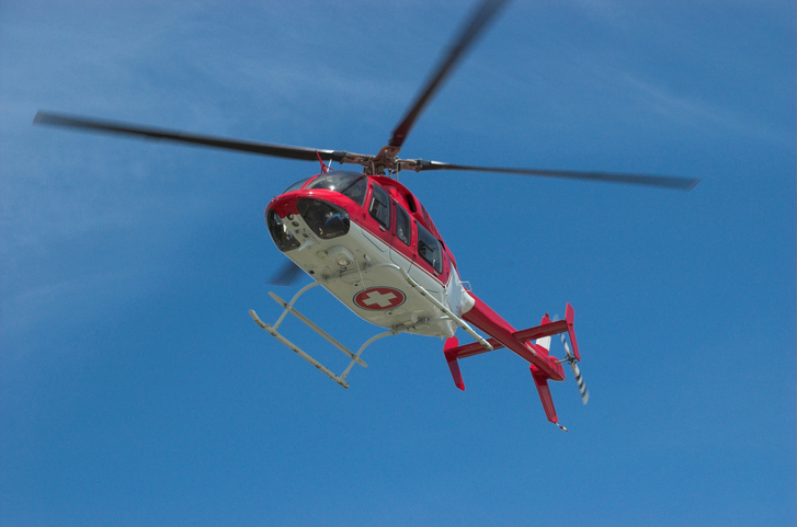 Closeup of flying red helicopter in contrast with blue sky