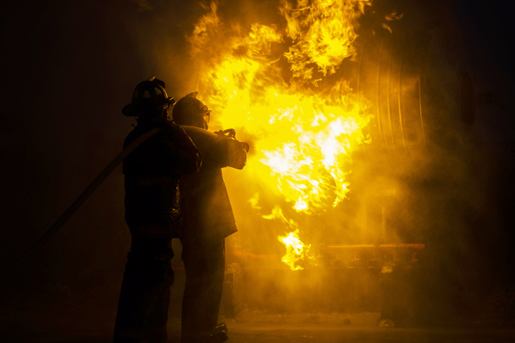 Rear View Of Firefighters Spraying Water On Fire