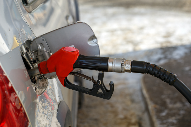 silver metallic car refueling on winter day gas station - close-up with selective focus and blurry background