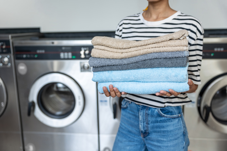 Unrecognizable woman in laundromat holding towels after using commercial washer