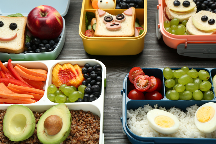 Lunch boxes with different snacks on wooden table, closeup