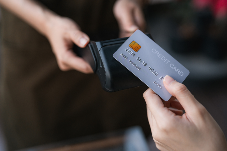 Young woman tapping her credit card on the waitress's device, embracing the ease and speed of contactless payment