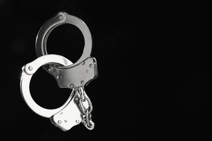 Metal chain handcuffs on black background, closeup. Space for text