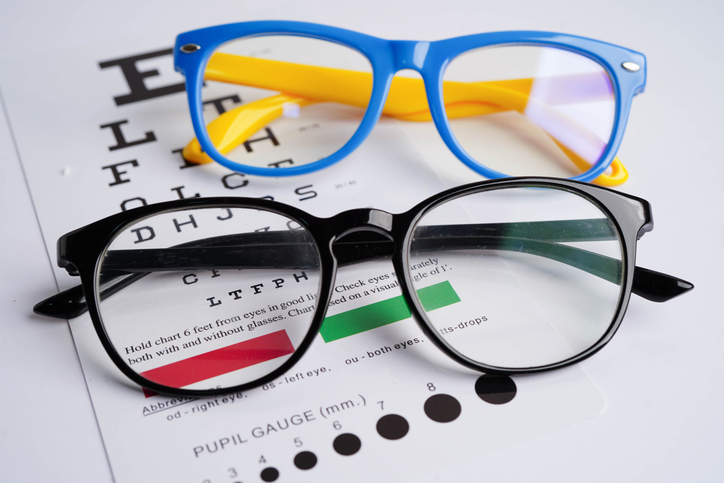 Glasses on eye exam chart to test eyesight accuracy of reading.