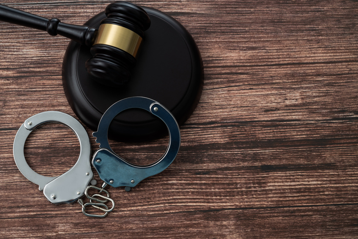 Gavel and handcuffs on wooden table