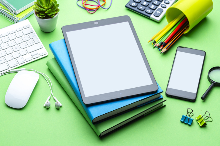 Digital tablet and smartphone mockup, blank screen devices. School or office supplies composition. Green background, working or studying using technology