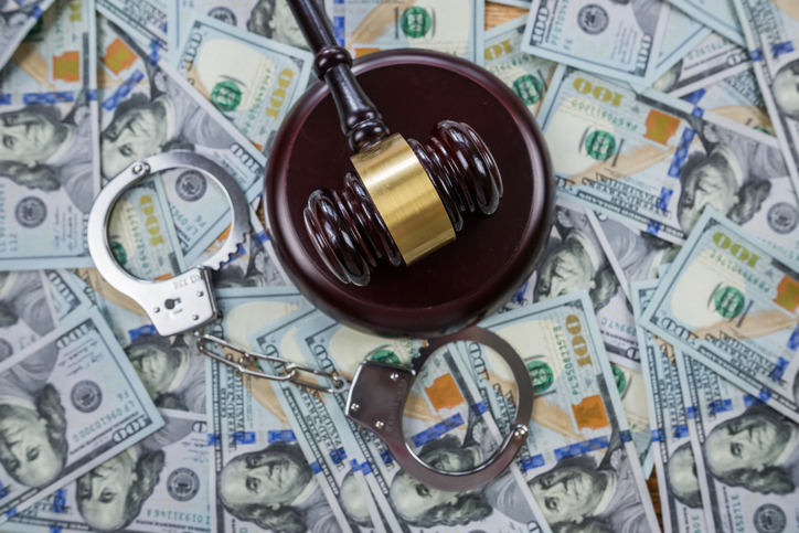 Judge's gavel with handcuffs on the background of dollar bills.