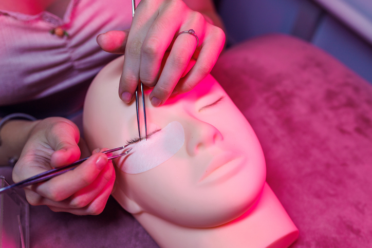 Eyelash extension training on a mannequin with professional tools for mastering lash techniques