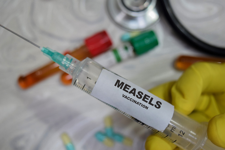 Measels vaccination drug syringe in yellow gloved hands. Medical concept